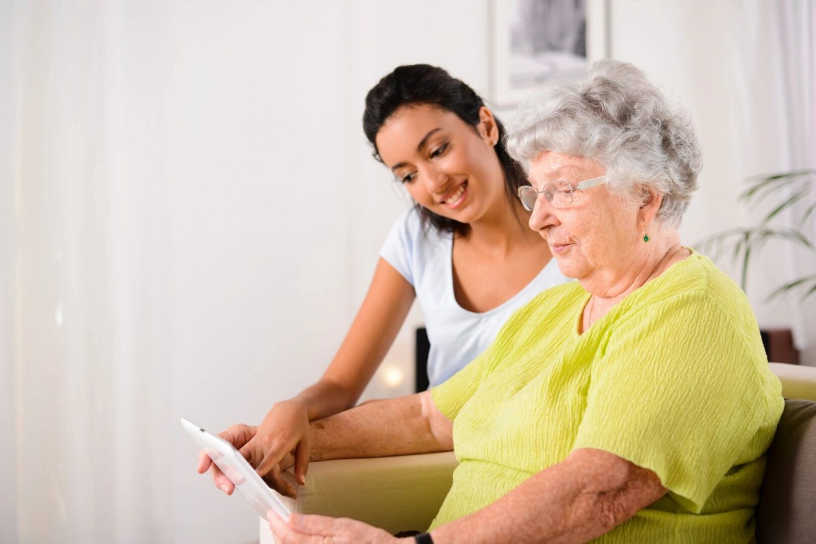 A woman and an older person looking at something on a tablet.