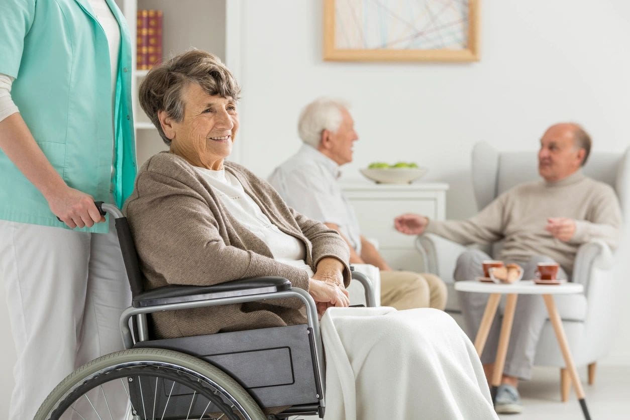 A woman in a wheelchair is sitting next to two other people.